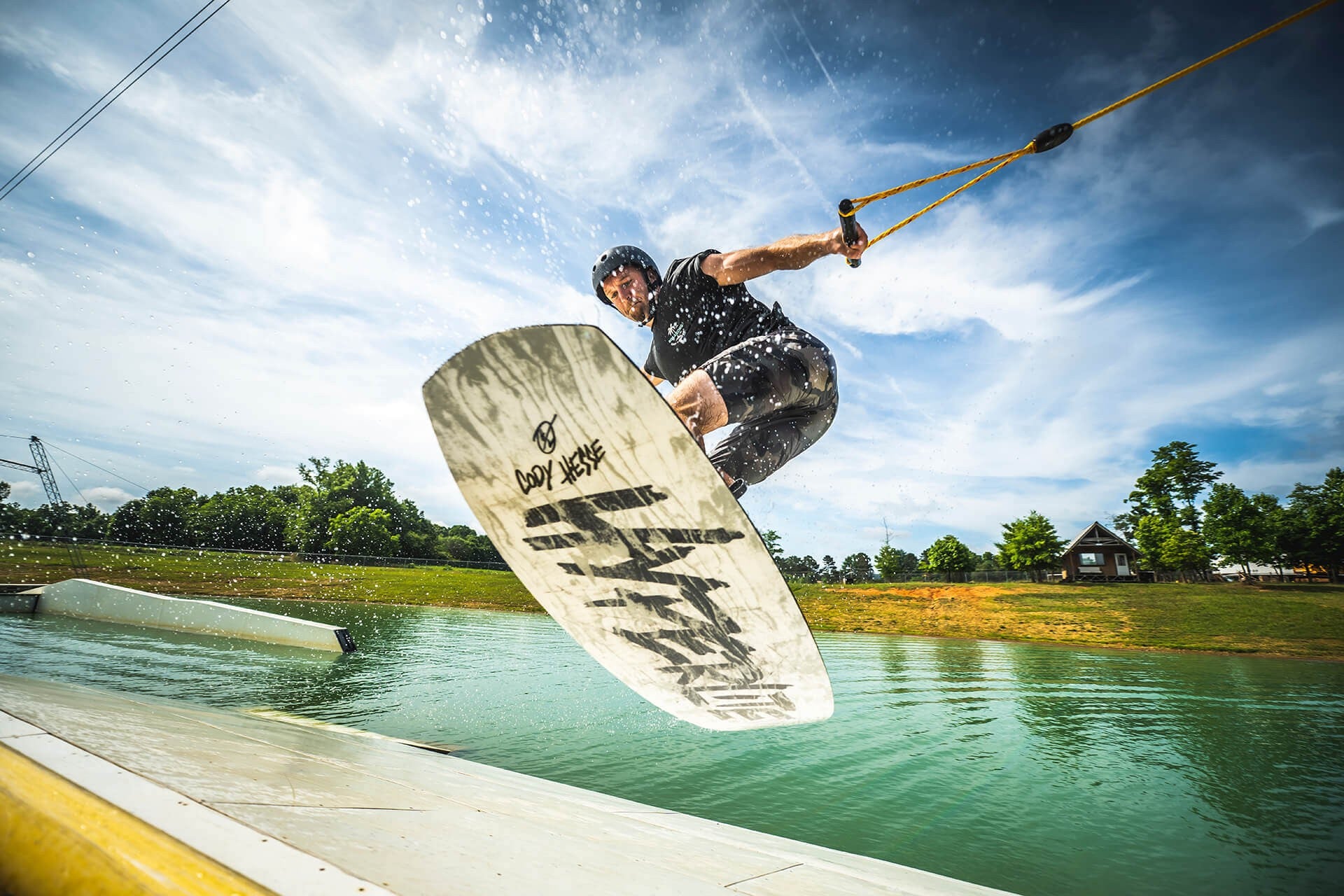 Wakeboarder off a kicker at a cable park
