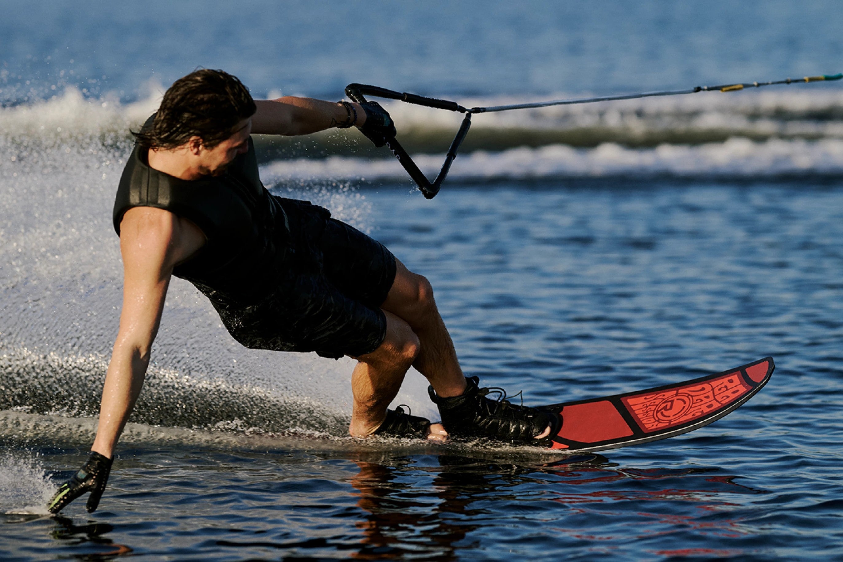 Slalom water skier carving hard on a red ski